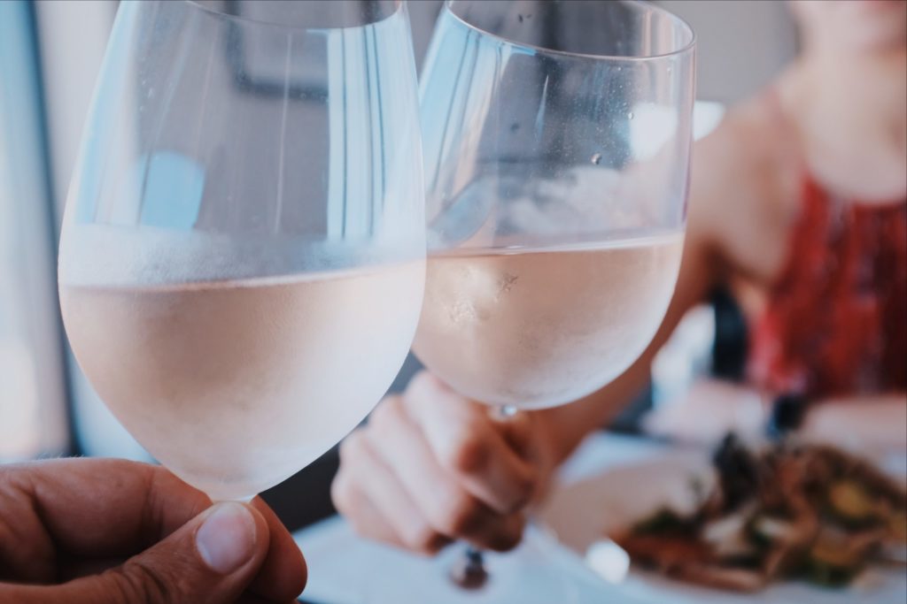 Deux verres de rosés bien frais qui trinque à table en arrière-plan une dame floutée