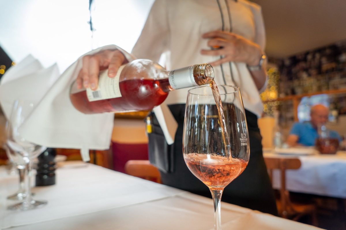 Un serveur sert Du vin rosé bien frais servi dans un beau verre