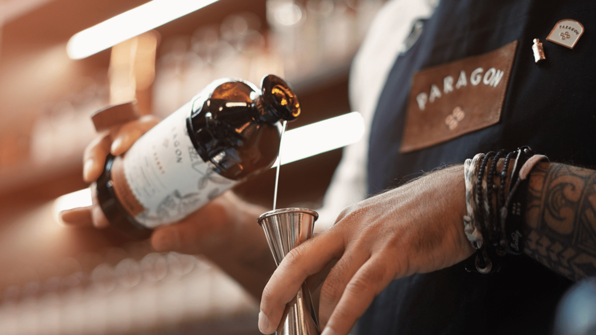 Barman d'un bar à cocktails parisien dosant du Cordial Monin Paragon Pepper pour sublimer son Cocktail